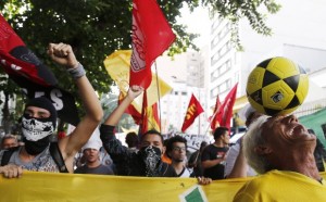 A man controls a soccer ball as various social and political groups march during a protest against the privatization of the Maracana Stadium in Rio de Janeiro